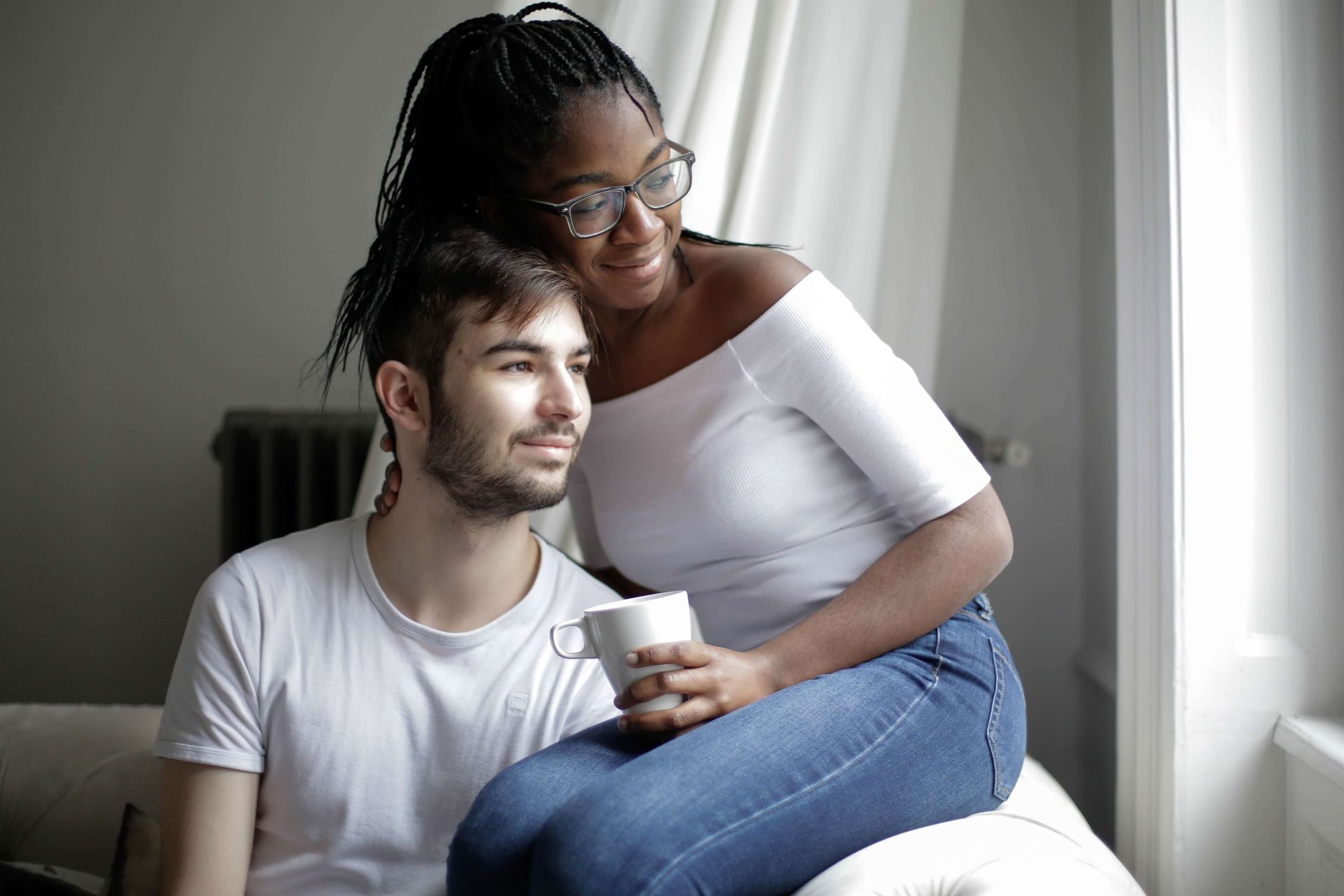 A woman sits on the arm of a couch next to her partner after reconnecting at a Hold Me Tight® Couples Retreat in Florida. Couples Retreats are available to couples in Florida and throughout the United States.