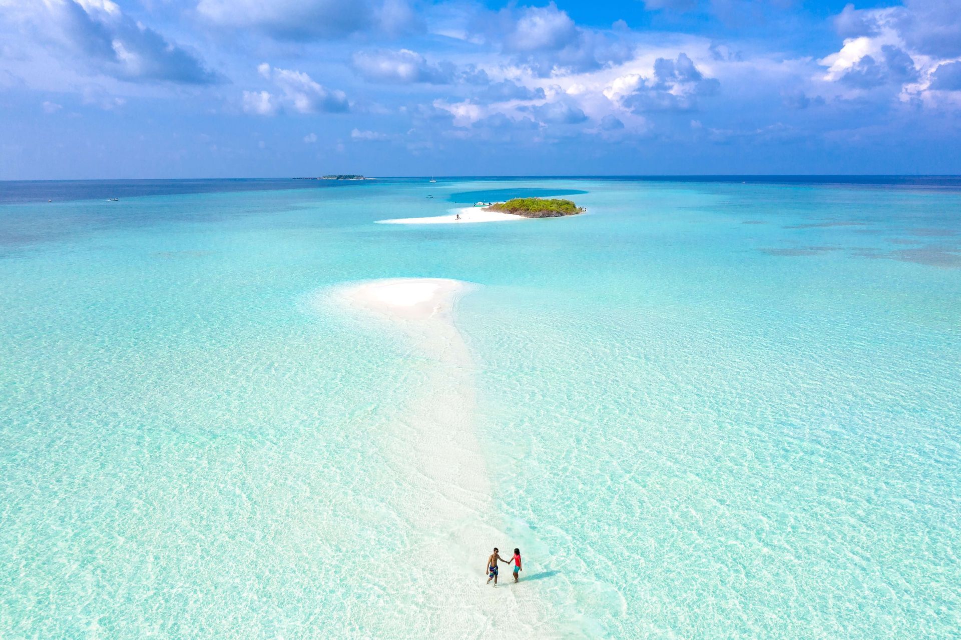 A couple holds hands while they walk in the ocean representing a couple who has overcome adversity in their relationship at a Couples Retreat in Orlando, FL. Couples Retreats are a great tool to build a lasting connection and are available in Orlando, FL and throughout the United States.