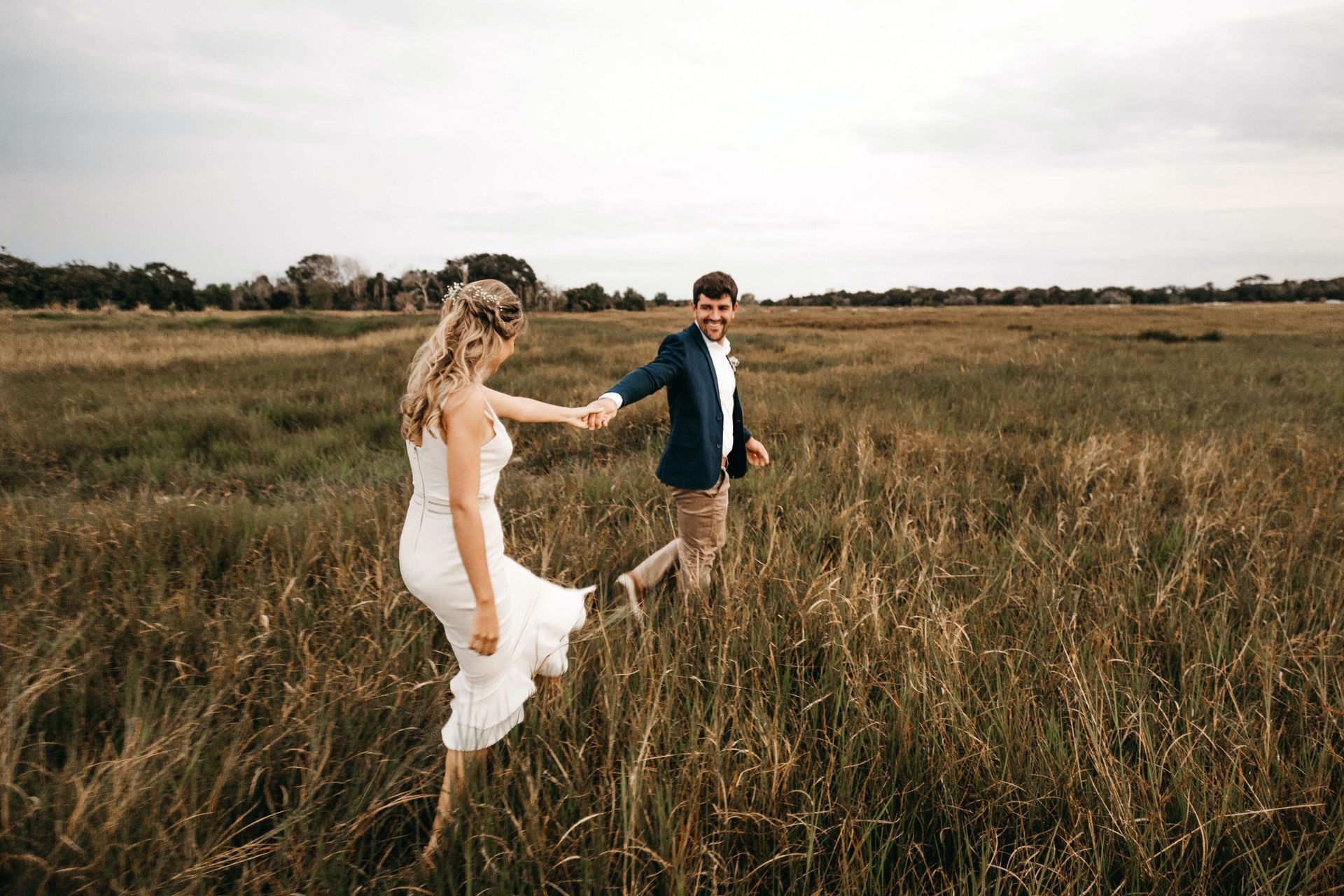 A young couple hold hands as they run through a grassy field representing the joy that can be found in your relationship as you reconnect at a Couples Retreat in Orland, FL. Couples Retreats are available to anyone in the United States and beyond.