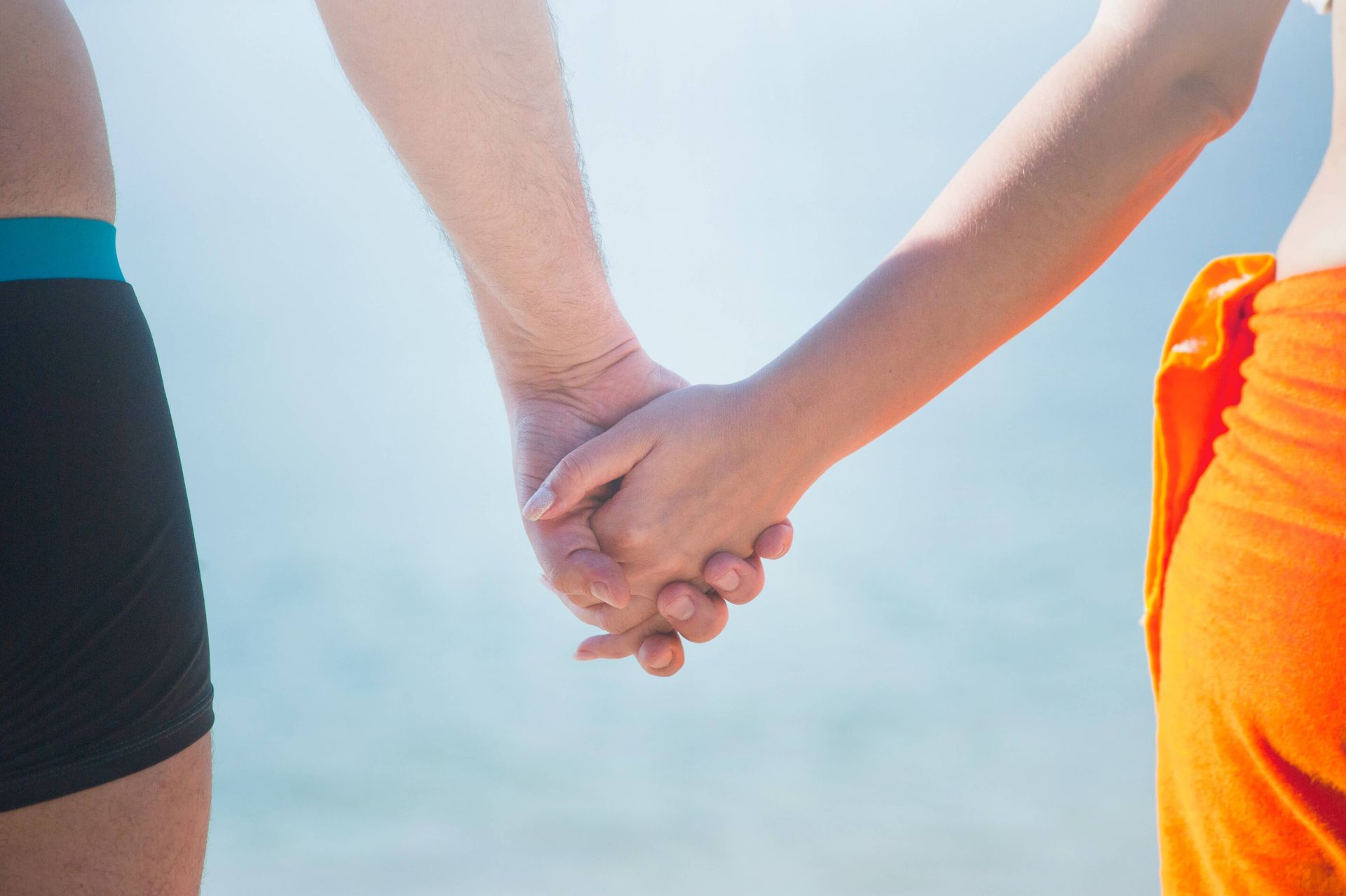 A couple holds hands on the beach after completing a Couples Retreat in Orlando, FL. Attend a Couples Retreat today, available to couples throughout the United States.
