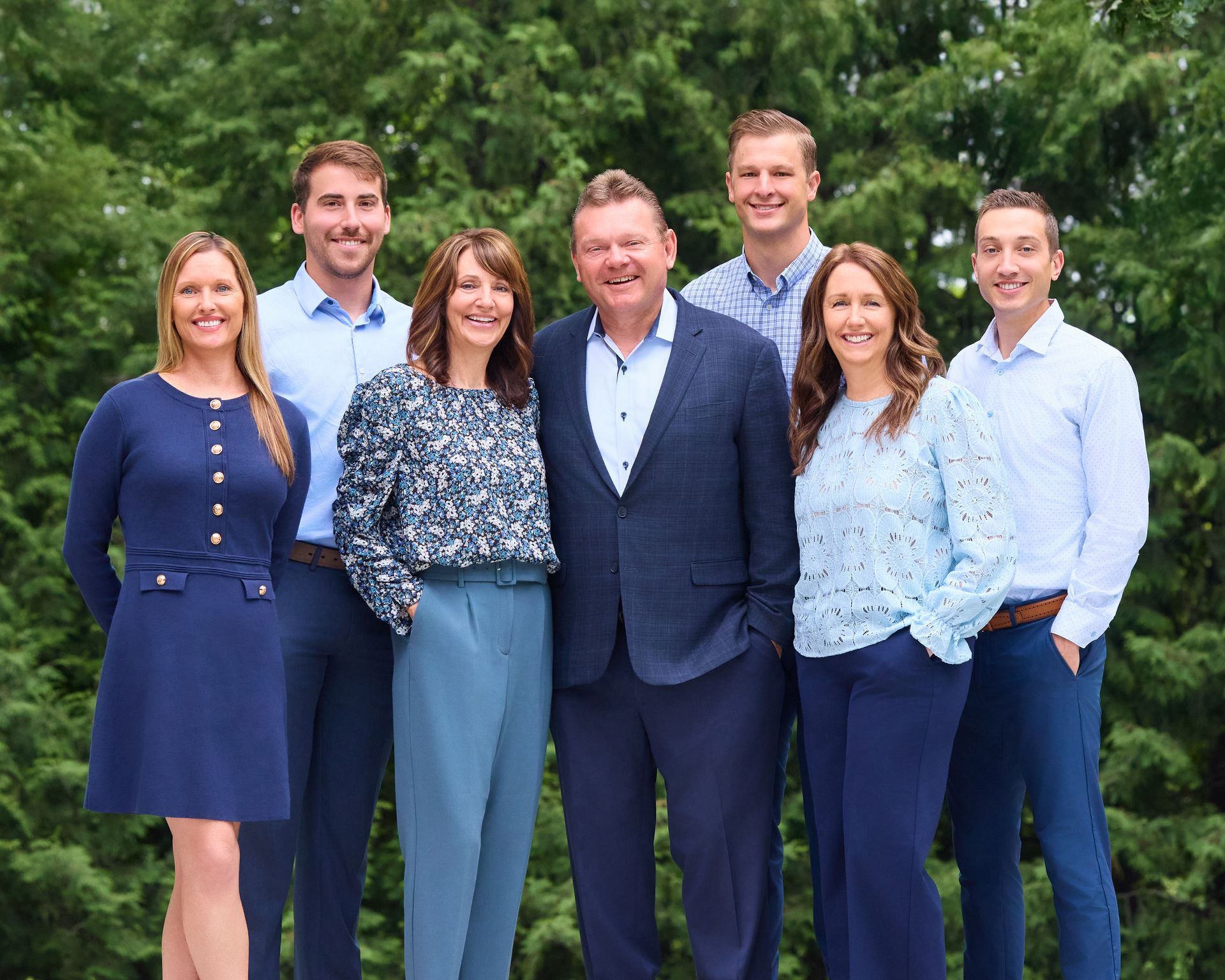 A group of people are posing for a picture in front of a framer retirement sign.