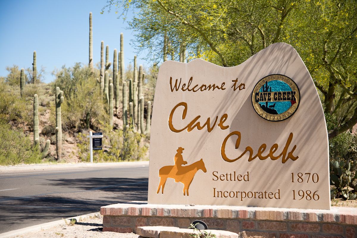 Sign welcoming visitors to Cave Creek, Arizona. Features a cowboy on a horse.