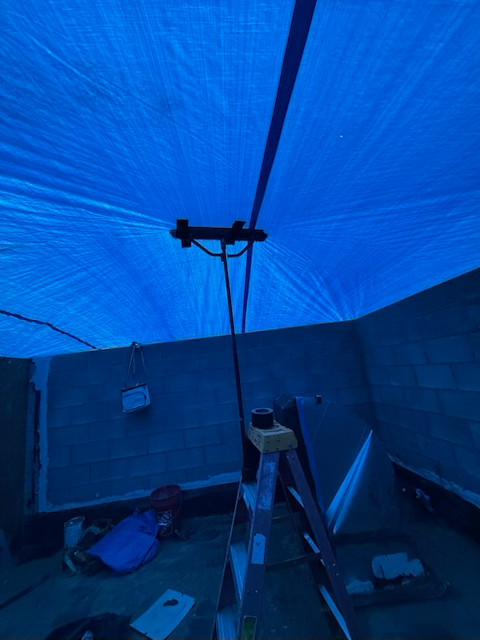 Person using a torch to install roofing material on a flat roof.