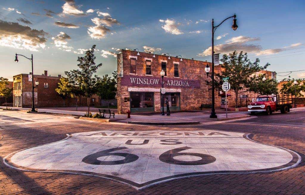 Route 66 landmark in Winslow, Arizona, with mural, old truck, and streetscape under a sunset sky.