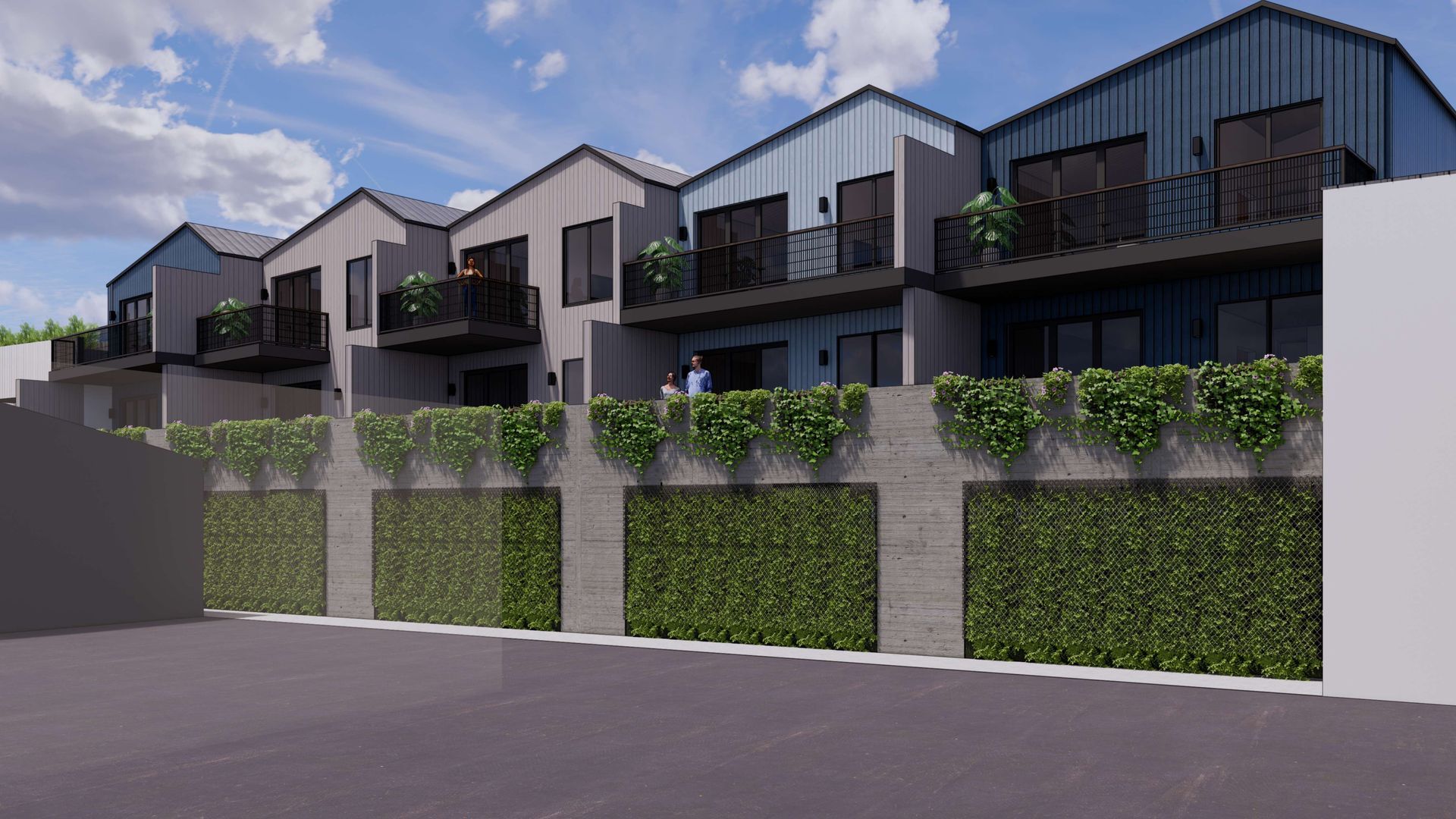 Row of modern townhouses with balconies, blue and gray siding, and a green hedge wall.