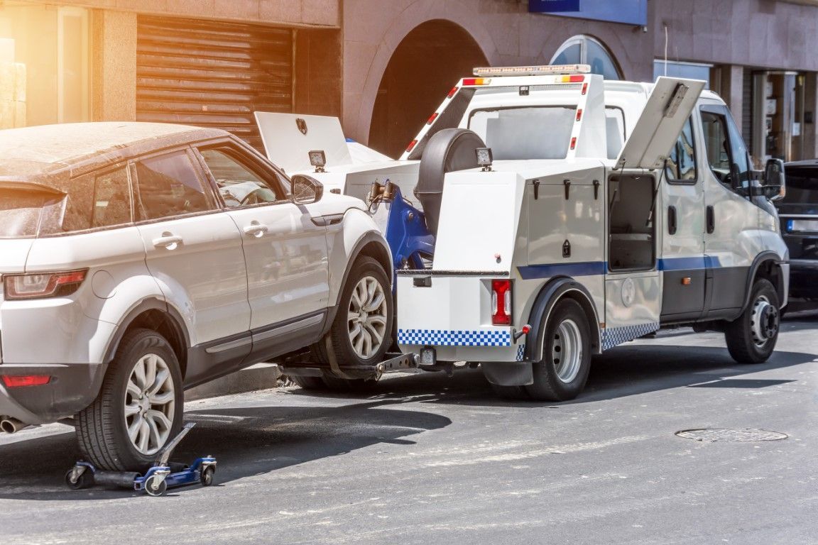 A white tow truck tows a white SUV in Mount Vernon
