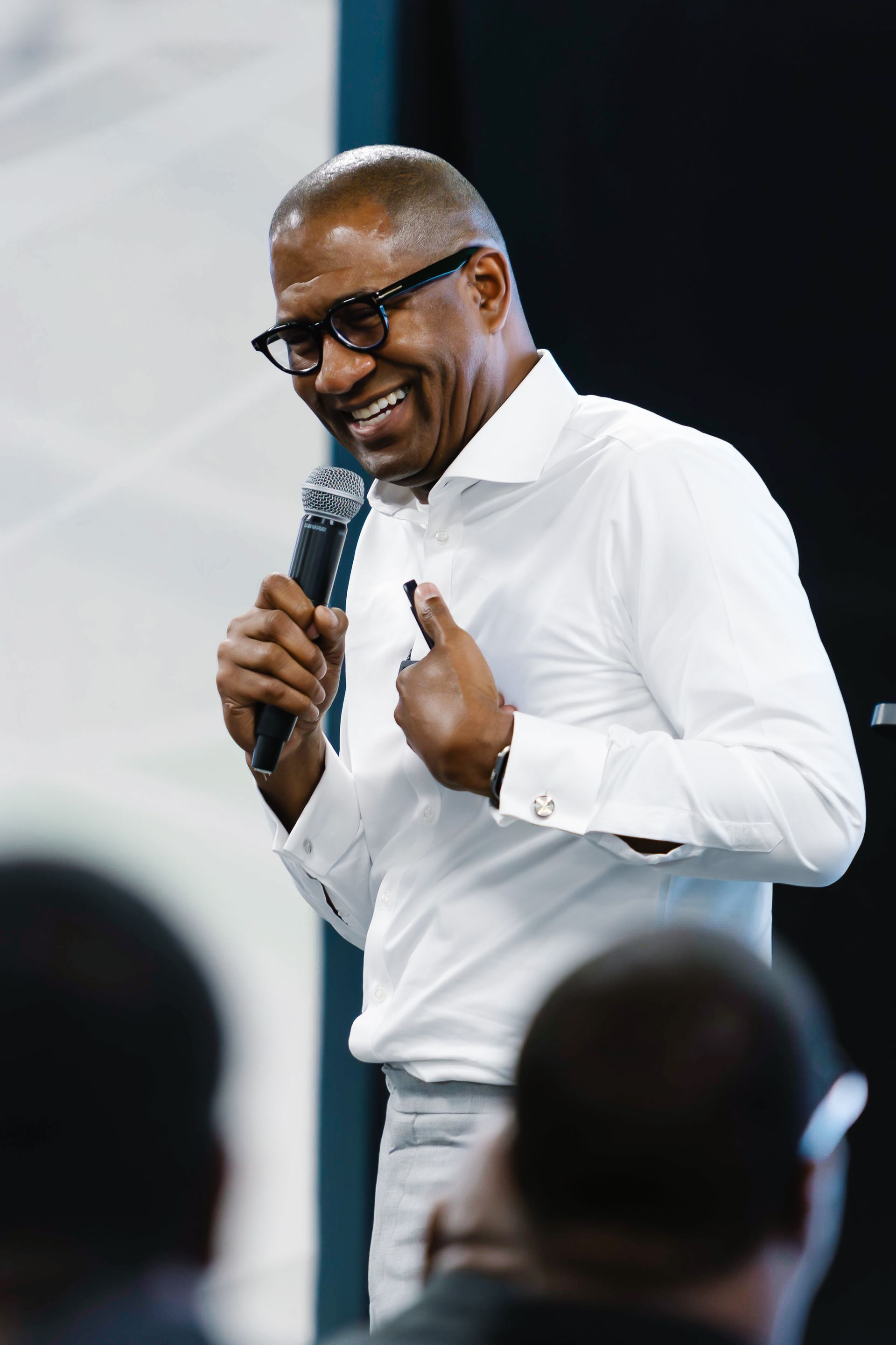 Brian Carter in white shirt speaks into a microphone, gesturing with both hands.