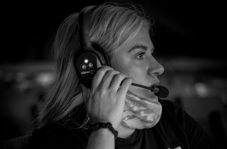 Woman in headset, face mask, looking focused.
