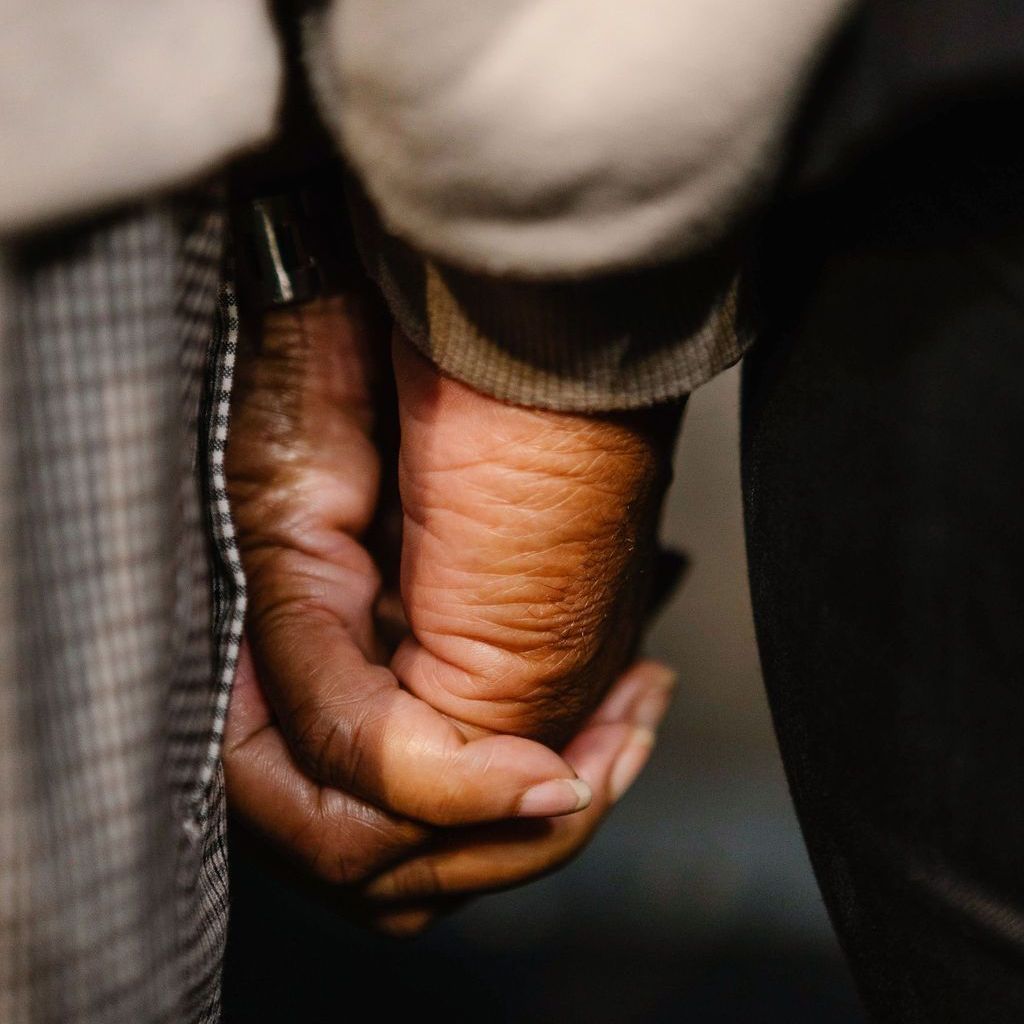 Close-up of two hands, one dark-skinned and one light-skinned, clasped together.