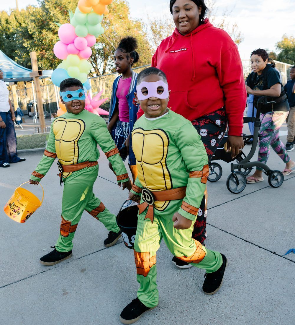Two kids in turtle costumes walking with family at last year's Harvest Carnival