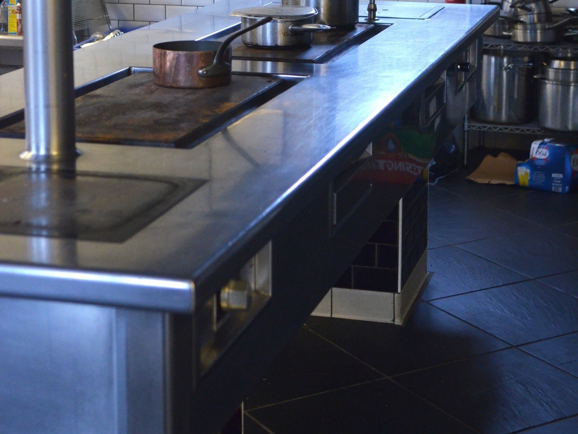 A stainless steel counter top in a kitchen with pots and pans on it