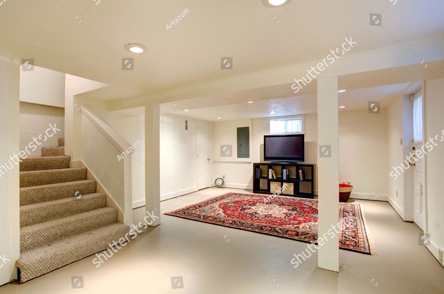 A living room in a basement with stairs and a television.
