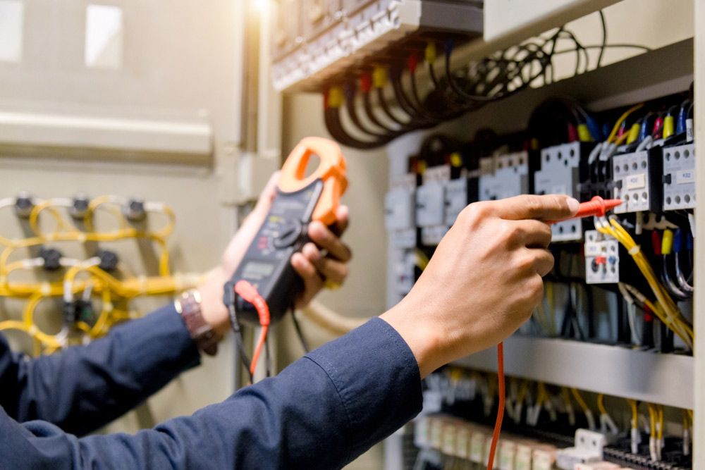 An Electrician is Working on an Electrical Panel With a Multimeter — Gealy's Air-Conditioning, Refrigeration & Electrical in Hervey Bay, QLD
