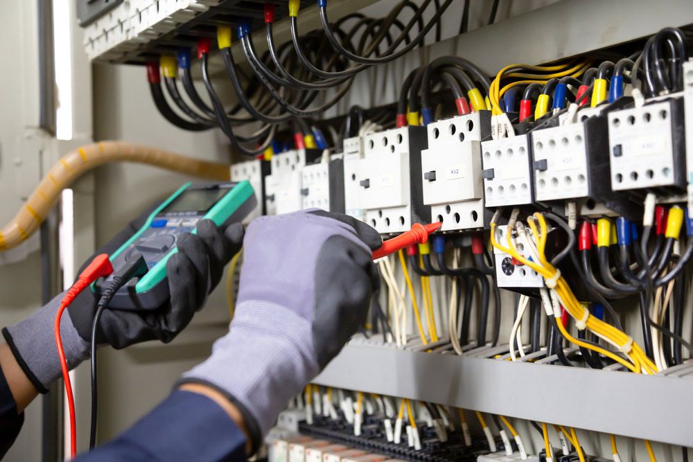 An Electrician is Working on an Electrical Panel With a Multimeter — Gealy's Air-Conditioning, Refrigeration & Electrical in Hervey Bay, QLD