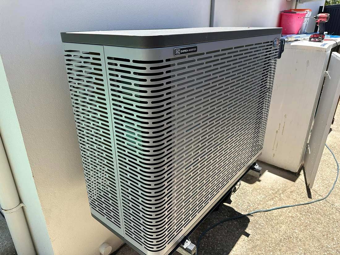 A Large Air Conditioner is Sitting on the Side of a Building — Gealy's Air-Conditioning, Refrigeration & Electrical in Caloundra, QLD