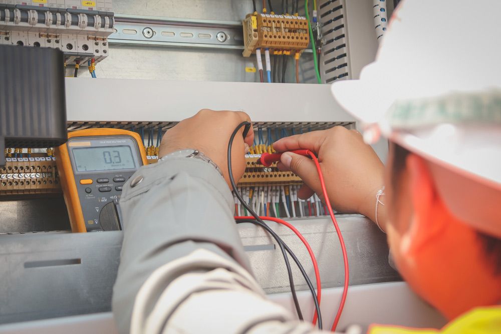 An Electrician is Working on a Circuit Board With a Multimeter — Gealy's Air-Conditioning, Refrigeration & Electrical in Tewantin, QLD