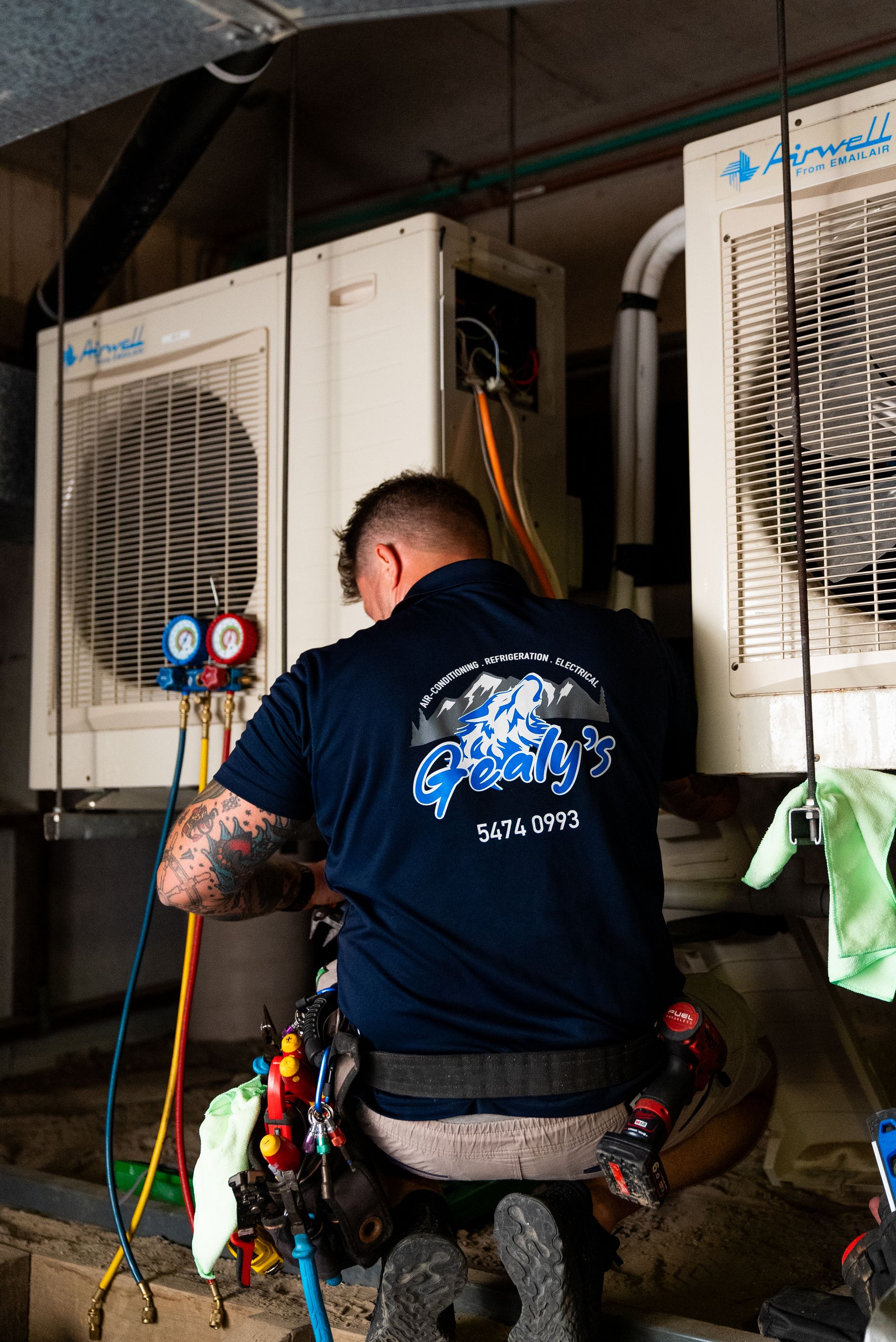 a man is facing away and wearing a business uniform while working on airconditioning systems— Gealy's Air-Conditioning, Refrigeration & Electrical in Noosaville, QLD