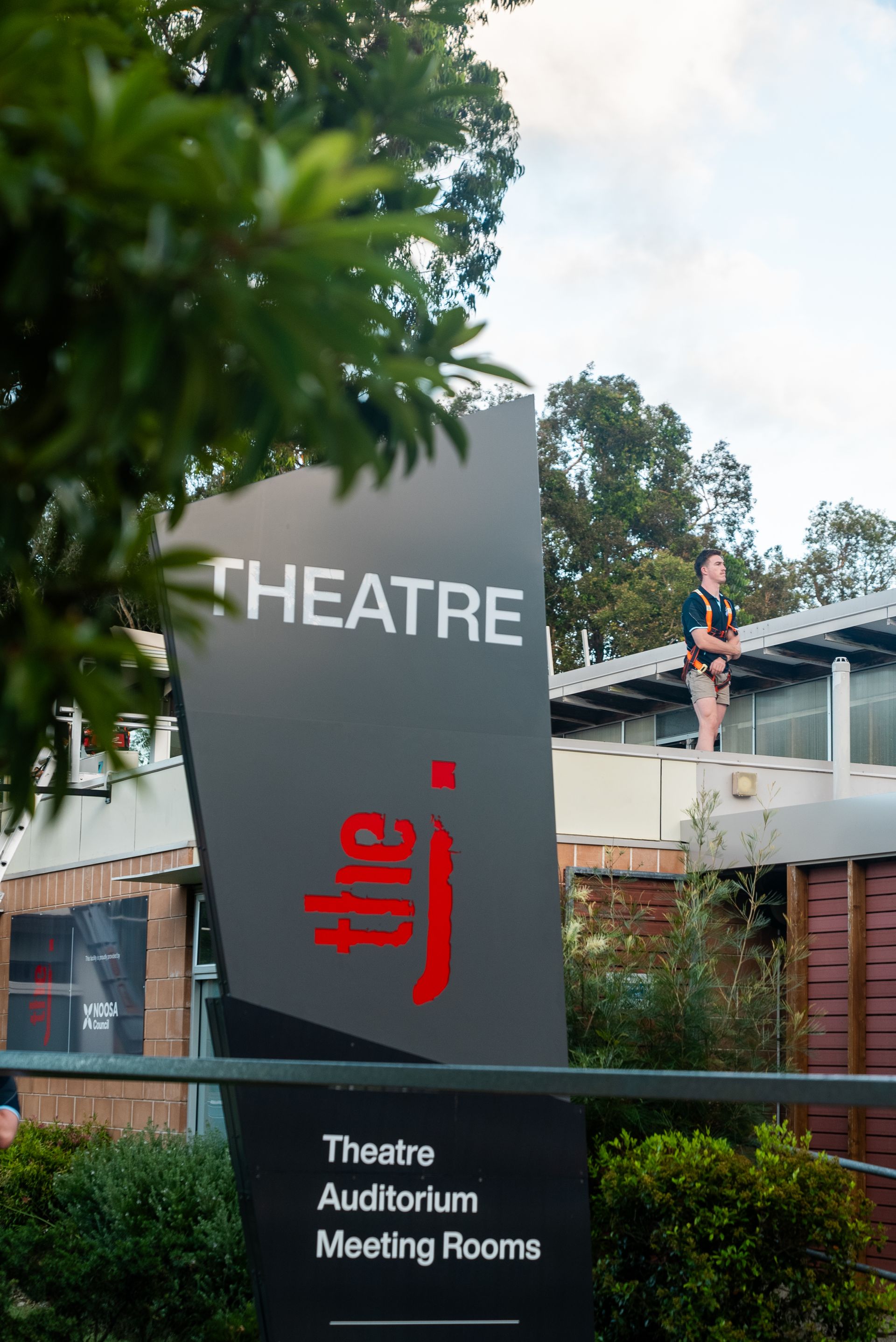 A man is standing on the roof of a building— Gealy's Air-Conditioning, Refrigeration & Electrical in Noosaville, QLD