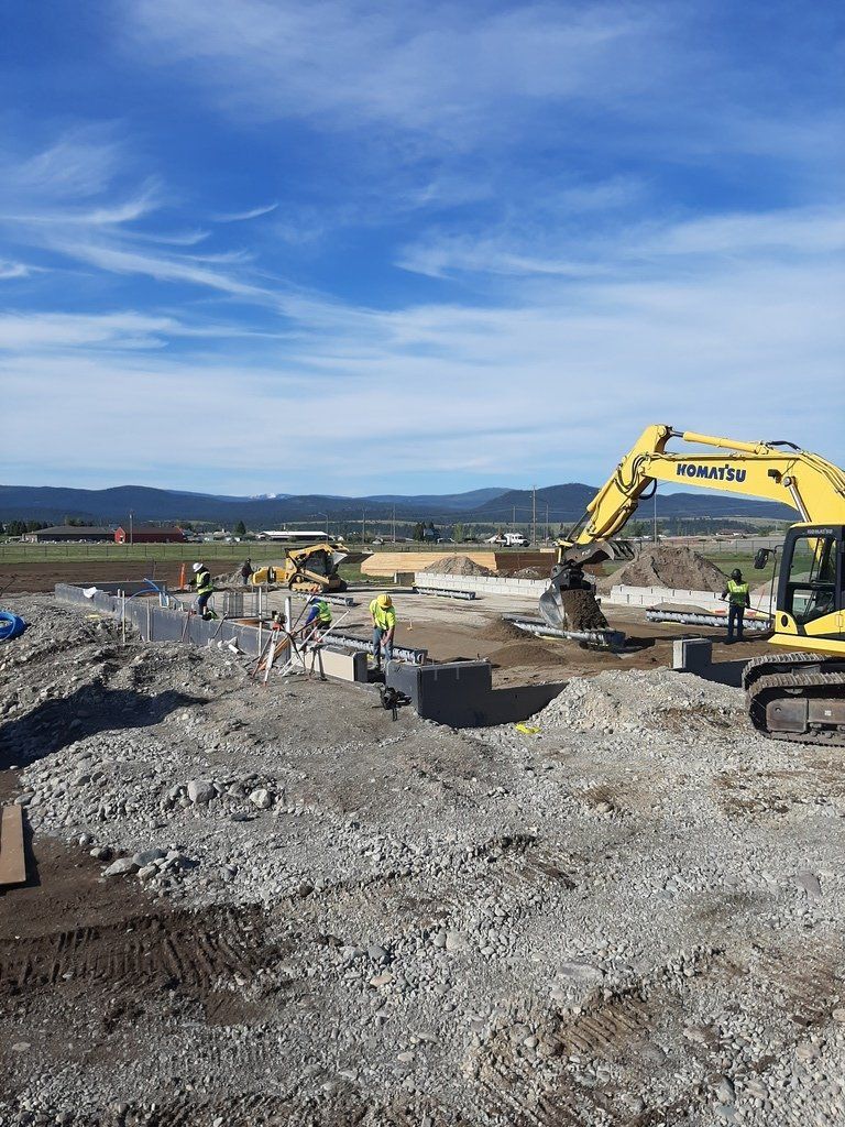 A large yellow excavator is working on a construction site.