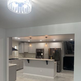 Modern kitchen with gray cabinets, island, and stainless steel appliances.