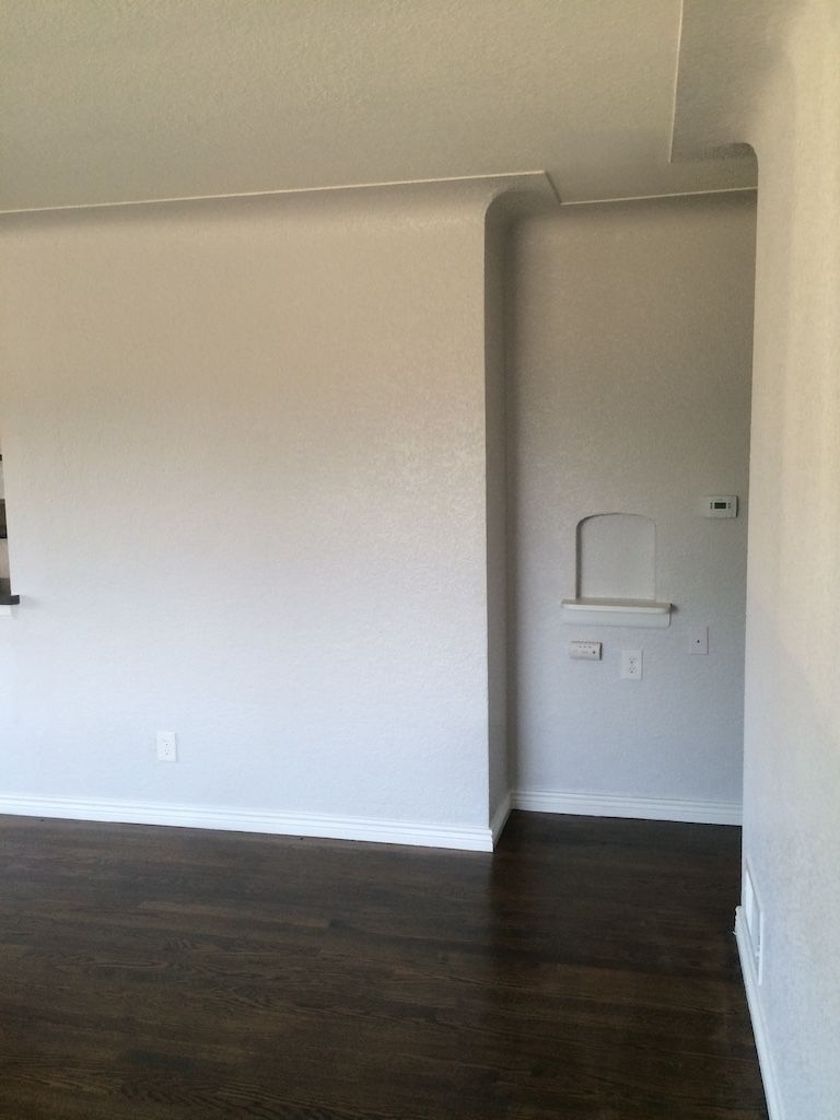 Interior view of a room with gray walls, dark wood floor, and a recessed wall area with electrical outlets.