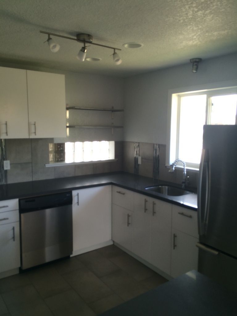 Kitchen with white cabinets, stainless steel appliances, and dark countertops.
