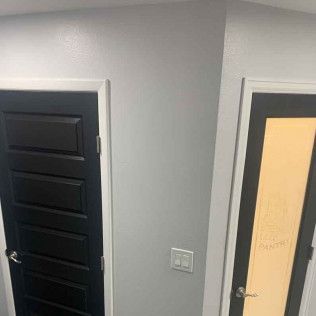 Two doors: one black, one with yellow frosted glass. Gray walls, white trim, light switch.