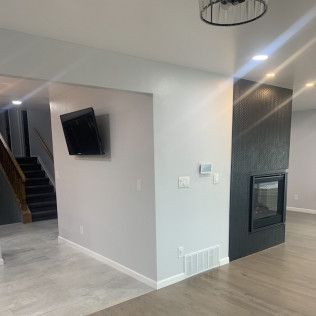 Interior view of a modern living space with a TV on the wall, fireplace, and staircase.