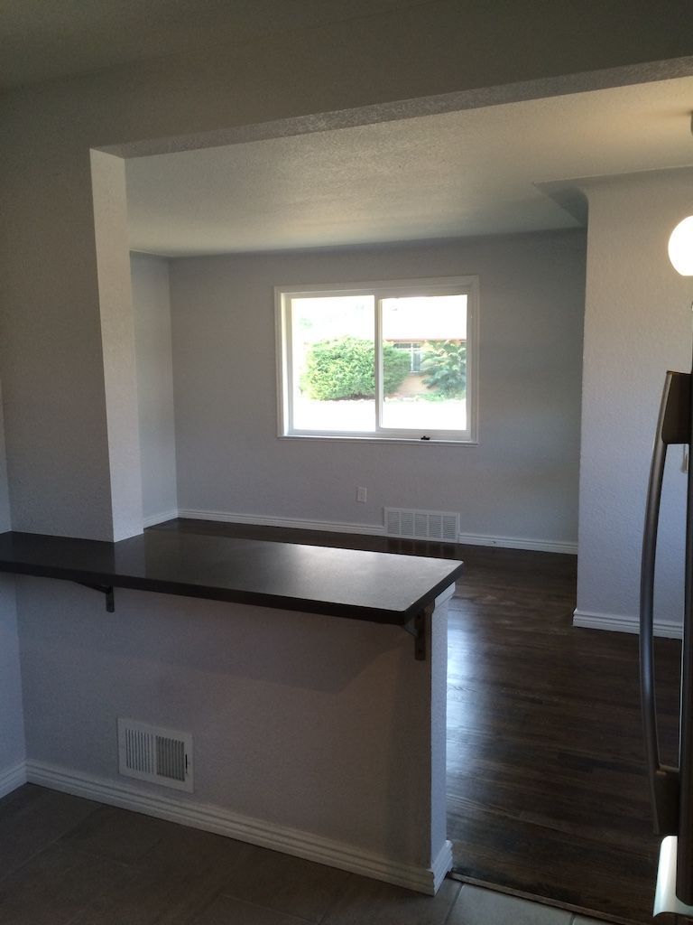 Interior view: doorway to a room with a window, dark wood countertop, and gray walls.