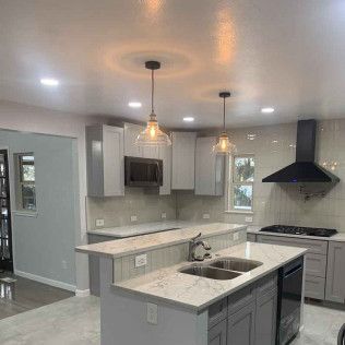 Modern gray kitchen with an island, countertops, cabinets, and range hood.