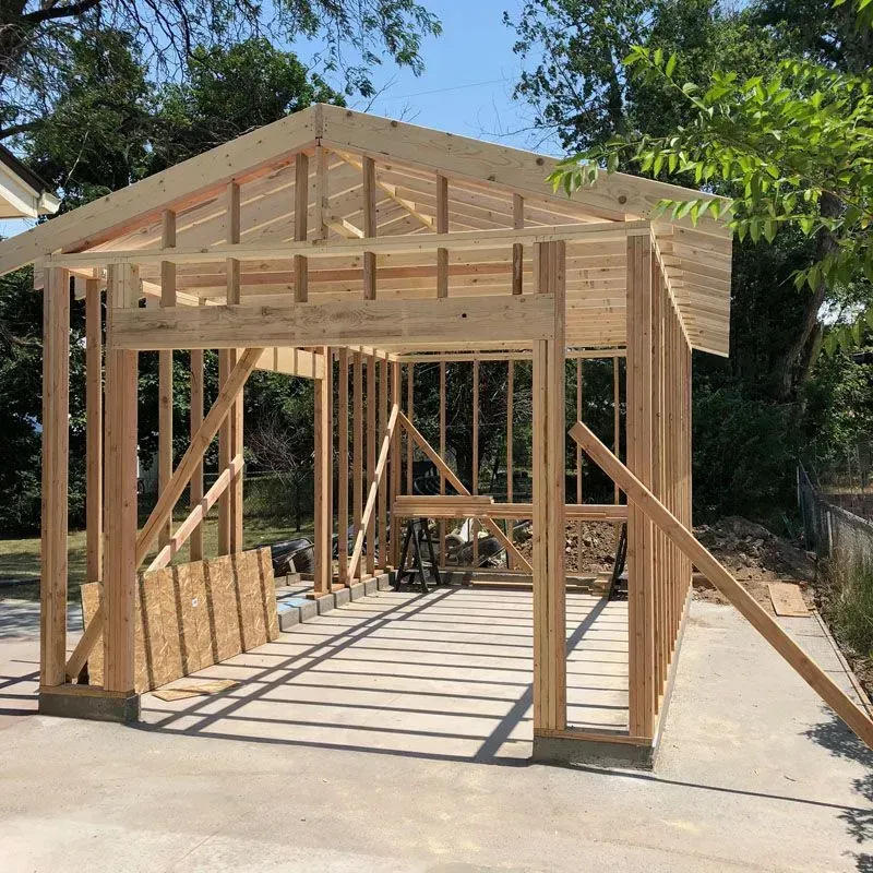 Wooden frame of a garage under construction on a concrete slab, outdoors.