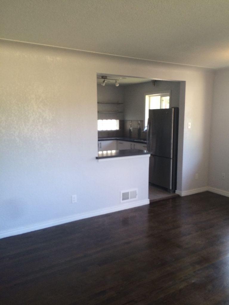 Living room with dark wood floors, a pass-through to a kitchen with stainless steel appliances.