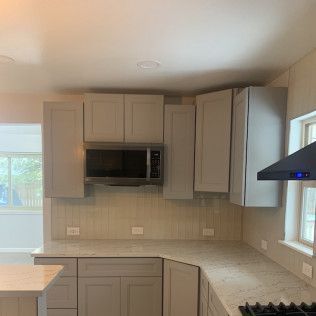 Gray kitchen with cabinets, countertop, microwave, and range hood.