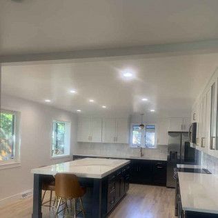 Modern kitchen with white upper cabinets, dark island, and light countertops.