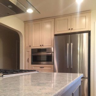 Kitchen with light cabinets, stainless steel refrigerator and built-in microwave, and granite countertop.