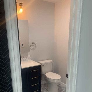 Bathroom with toilet, sink, and medicine cabinet, viewed through an open doorway.