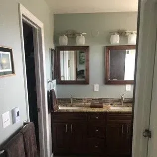 Bathroom with double vanity, mirrors, and wood cabinetry.