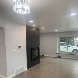 Living room with fireplace, gray walls, recessed lighting, and a large window.