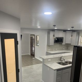 Gray kitchen with light countertops, cabinetry, and recessed lighting. Black door and appliances.