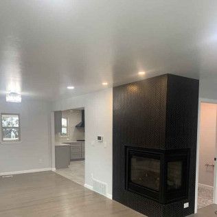 Living room with black tiled fireplace, gray kitchen visible in background.