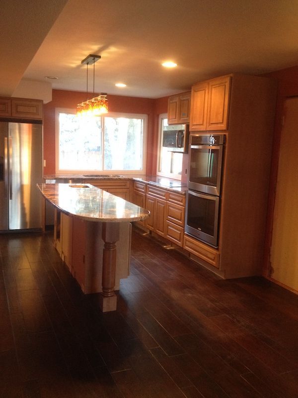 Kitchen with wood cabinets, island, stainless steel appliances, and dark hardwood floors.