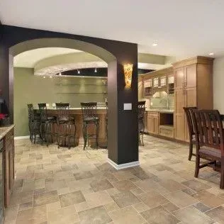Basement bar and dining area with tile floor, dark walls, and wood cabinets.