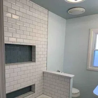 Bathroom with white subway tile shower, blue accent, and built-in niches.
