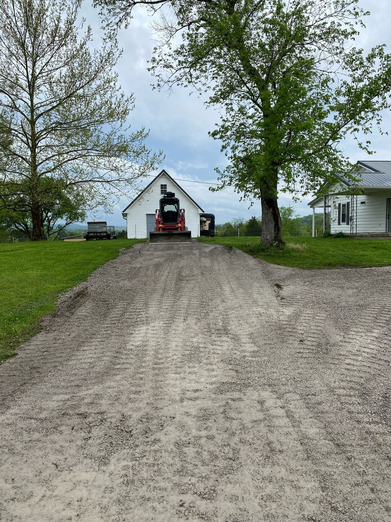 A truck is parked on the side of a dirt road in front of a house.
