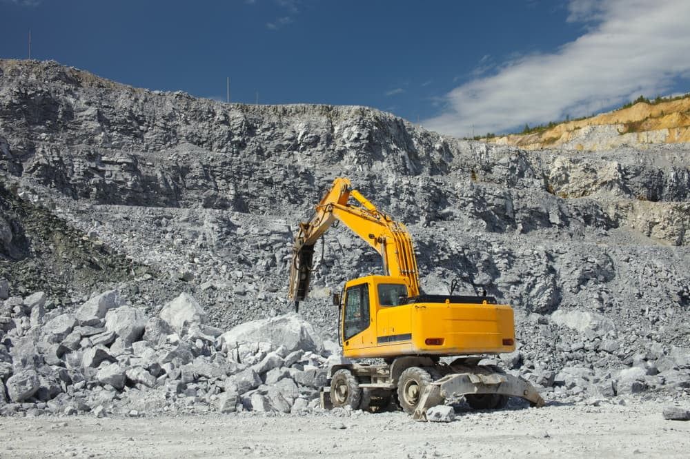 A Yellow Excavator is Working in a Rock Quarry — A & B Mullins Excavations Pty Ltd in Bungadoo, QLD