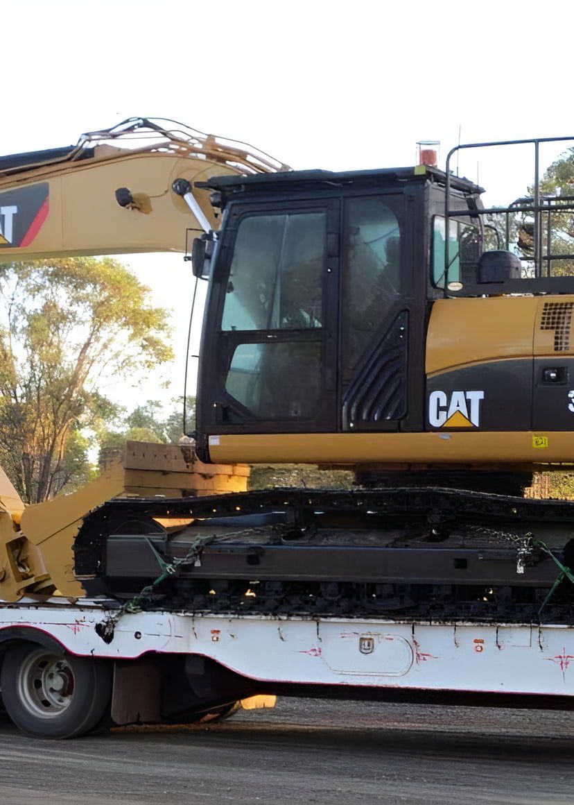 A Cat Excavator is Sitting on Top of a White Trailer — A & B Mullins Excavations Pty Ltd in Burnett Heads, QLD