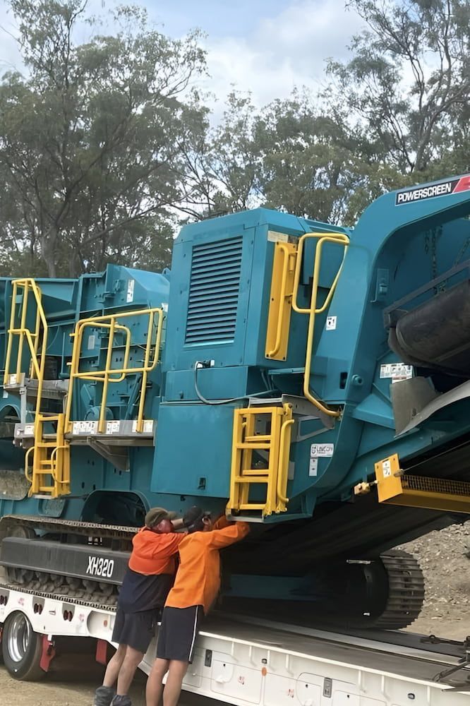 Two Men Are Standing Next to a Large Blue Machine on a Trailer — A & B Mullins Excavations Pty Ltd in Burnett Heads, QLD