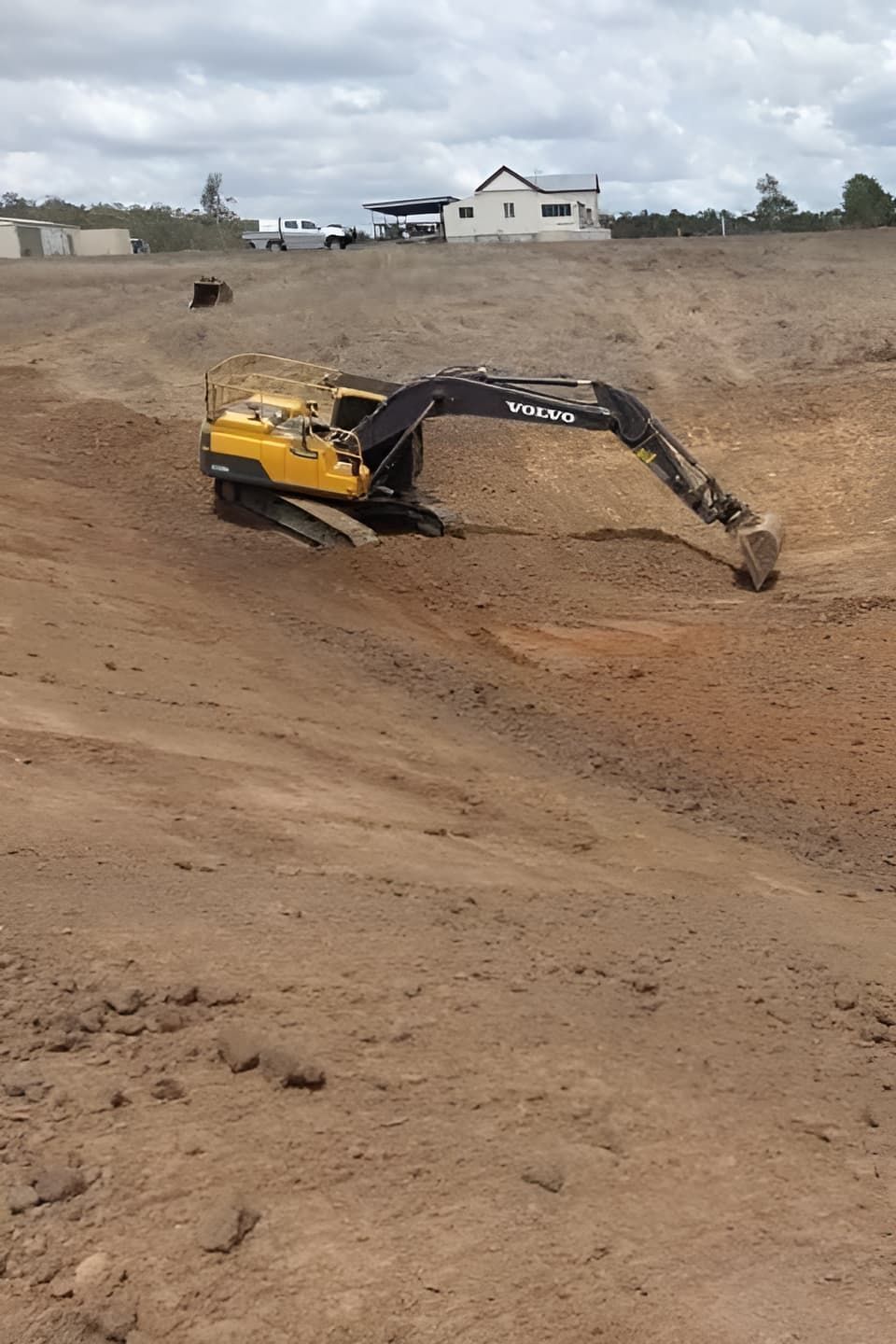 A Yellow Excavator is Digging in a Dirt Field — A & B Mullins Excavations Pty Ltd in Bungadoo, QLD