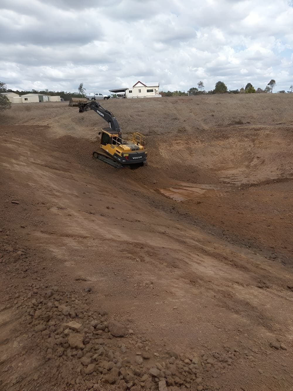 A Yellow Excavator is Driving Down a Dirt Road — A & B Mullins Excavations Pty Ltd in Bungadoo, QLD