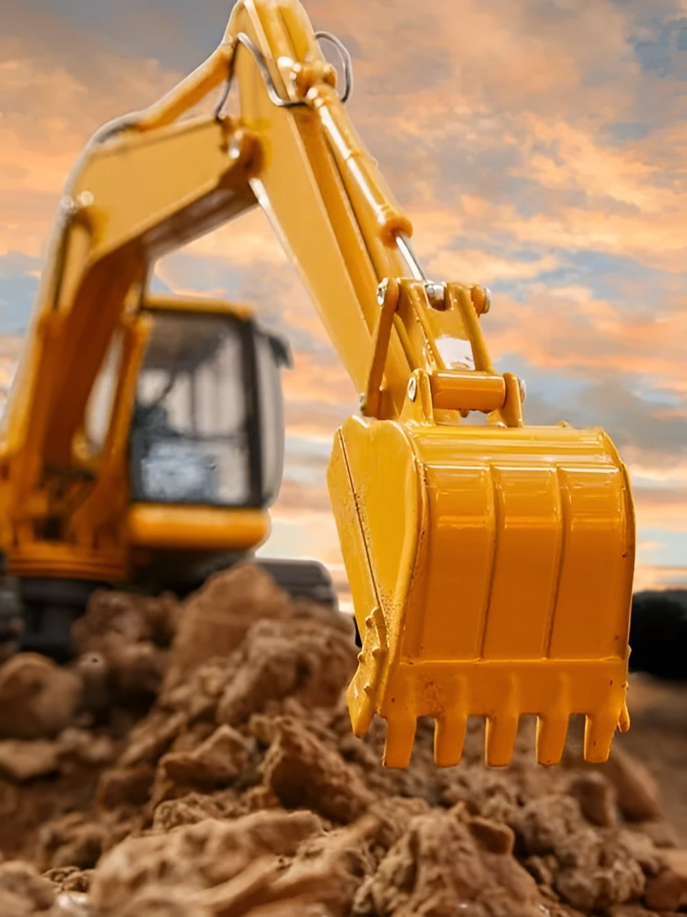 A Yellow Excavator is Scooping Dirt From a Pile of Rocks —  A & B Mullins Excavations Pty Ltd in Gin Gin, QLD